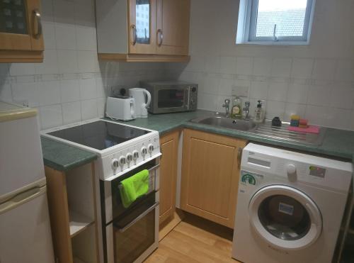 a kitchen with a stove and a washing machine at Star Apartment in Guildford