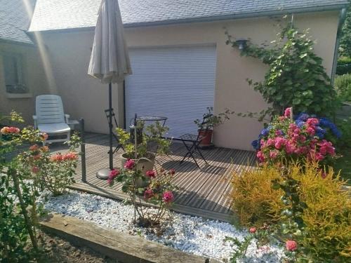 une terrasse arrière avec un parasol et des fleurs dans l'établissement Les hortensias, à Lannion