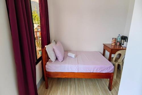a small bed in a room with a window at Kamalay Pension House in Nagpoyopoyo Island