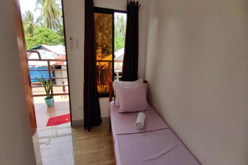 a room with a couch with a pillow and a window at Kamalay Pension House in Nagpoyopoyo Island