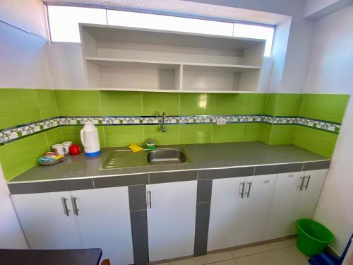 a kitchen with green and white cabinets and a sink at Marlen's Qorywasi in Cusco