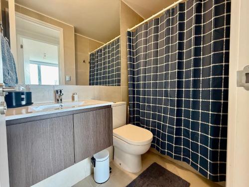 Un baño con inodoro, lavabo y espejo. en Nuevo y cómodo en Costa de Montemar, en Concón