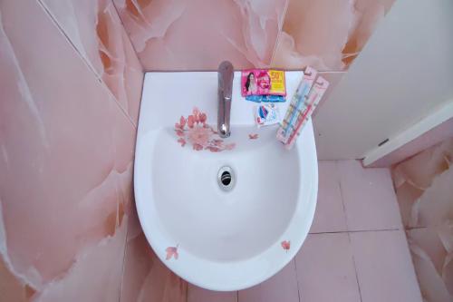 a white toilet in a bathroom with a pink wall at Kamalay Pension House in Nagpoyopoyo Island