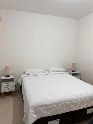 a white bedroom with a bed and two night stands at Apartamento próx ao CTG e Arena Opus São José in São José