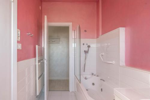 ein Badezimmer mit rosa Wänden und einer Badewanne und einer Dusche in der Unterkunft Casa ariel in Lecce