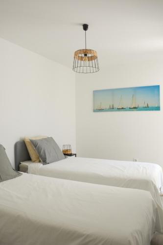 a white bedroom with two beds and a chandelier at Casa Luminosa - 160m to the beach, located in the Historical Center of Sesimbra in Sesimbra