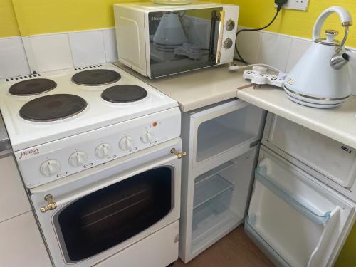 a kitchen with a white stove and a microwave at 4 Guests - Pet Friendly - Chalet Beach Home Chapel in Skegness