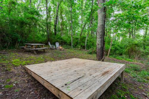 a wooden table and a picnic table in the woods at Hidden Hollow Campsite at Hocking Vacations - Tent Not Included in Logan