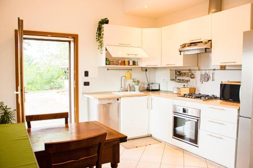 a kitchen with white cabinets and a wooden table at Stanza in Villa in mezzo al verde, vicino Bologna Via Erbosa 1B Budrio 40054 in Lupara