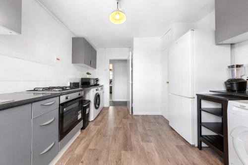 a kitchen with white appliances and a wooden floor at South Stays 2 in London