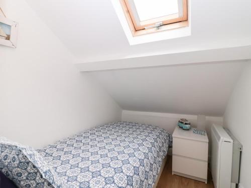 a small bedroom with a bed and a window at Smugglers Loft in Looe
