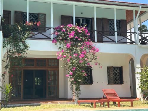 a red bench in front of a building with flowers at Madarisha House in Kilifi