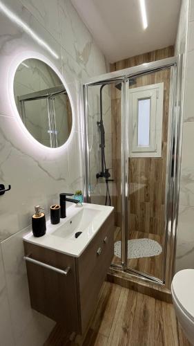 a bathroom with a shower and a sink and a mirror at Central Haven in Volos