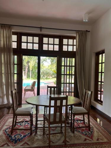 a dining room with a table and chairs and windows at Madarisha House in Kilifi