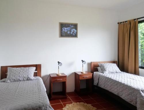 a room with two beds and a window at Hotel El Arca, Jardín Botánico y Restaurante in Santa Bárbaraa