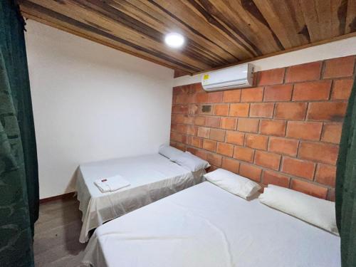 a small room with two beds and a brick wall at Villa Mercedes in La Dorada