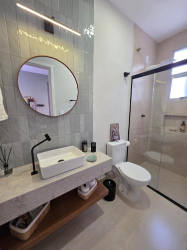 a bathroom with a sink and a toilet and a mirror at Seu Loft em BH, conforto e localização perfeita in Belo Horizonte