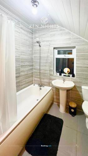 a bathroom with a bath tub and a sink at Last-minute Specials l Elegant House near City Center Sleeps 8 with Free Parking l Near DeMontfort Uni l By Zen Nights Short Lets & Serviced Accommodations in Leicester
