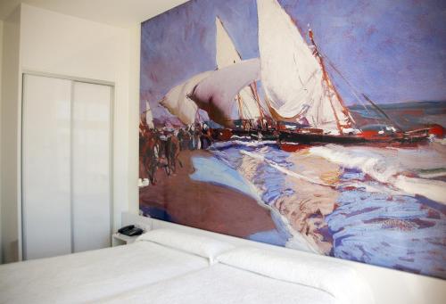 a bedroom with a painting of a sailboat on the wall at Sol Playa in Valencia