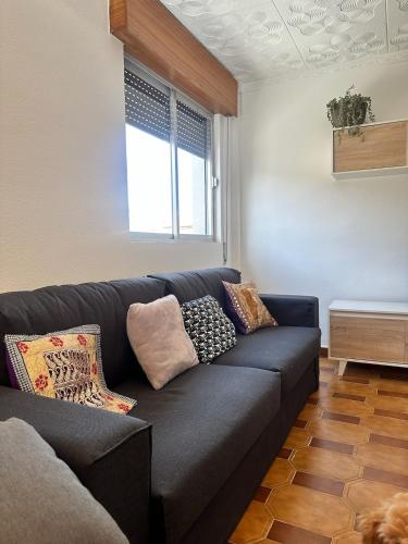 a living room with a black couch with pillows at Can Guzmu in Cijuela