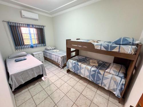a room with two bunk beds and a window at Casa p/ 11 hóspedes - 900m do Parque de Exposições in Patos de Minas