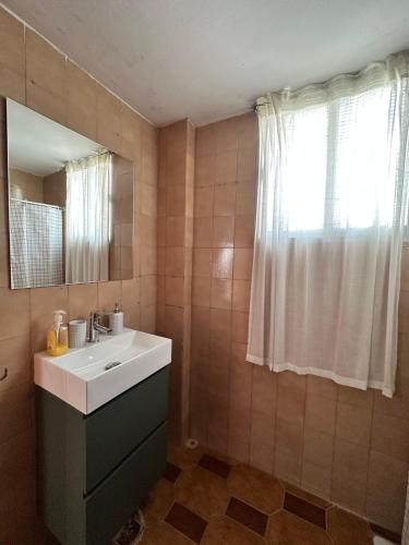a bathroom with a sink and a mirror and a window at Can Guzmu in Cijuela