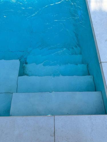 a pool of blue water with stairs in it at Can Guzmu in Cijuela
