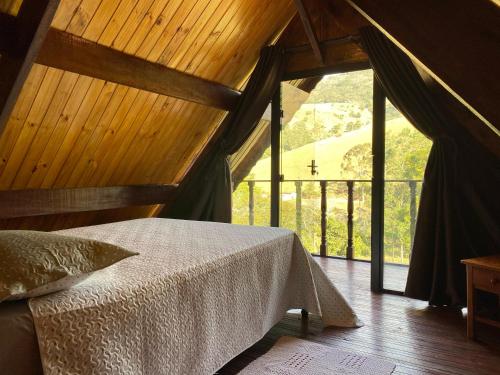 a bedroom with a bed and a large window at Recanto das Maritacas in Camanducaia
