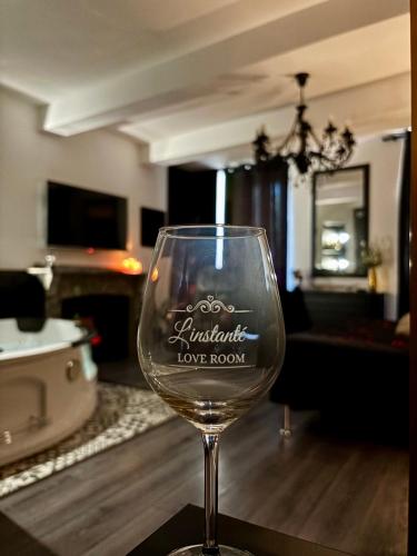 a wine glass sitting on a table in a living room at Love Room L'instanté - Suite "L'élégante" in Limoux