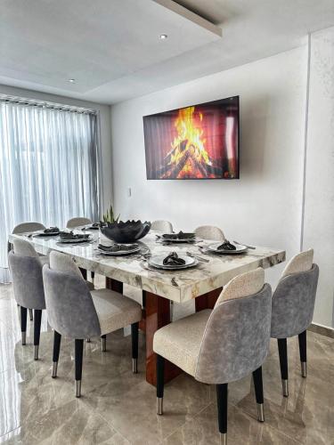 a dining room table with chairs and a television on the wall at Curiti Luxury House in Curití