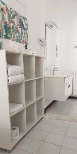 Un baño con estantes blancos, un lavabo y un espejo. en B&B Bixio 34, en Reggio Calabria