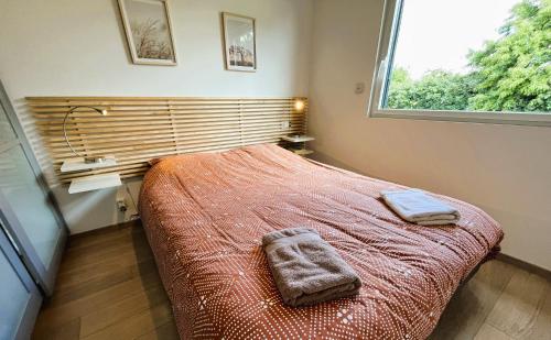 a bedroom with a bed with two towels on it at Belle maison en bois Perros - La lande in Perros-Guirec
