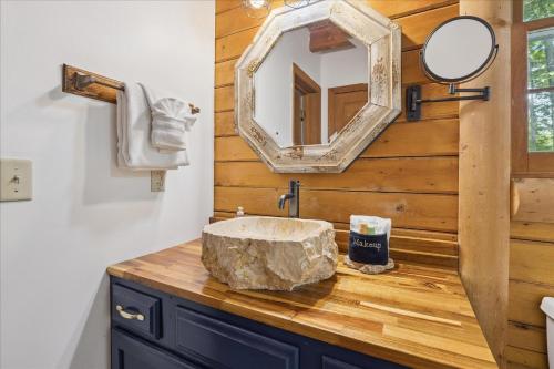 W łazience znajduje się kamienna umywalka i lustro. w obiekcie Cozy Timbers by Beyond Expectations w Hot Tub w mieście Rocky Grove
