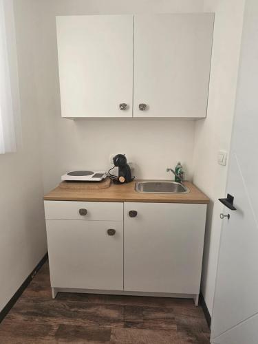 a small kitchen with a sink and white cabinets at La Vida Apartments in Babalonija