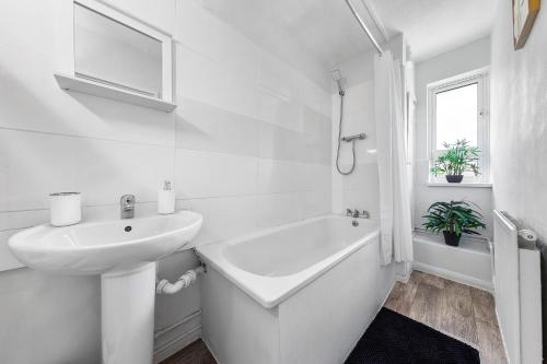 a white bathroom with a sink and a bath tub at South Stays 4 in London