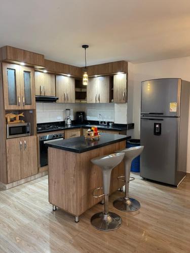a kitchen with wooden cabinets and a stainless steel refrigerator at Departamento Medellín bello in Bello