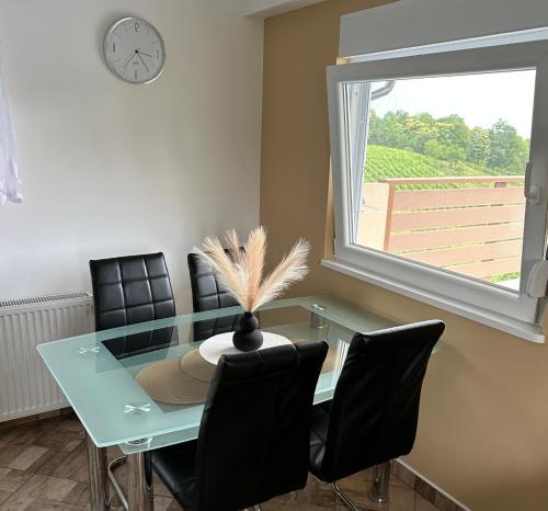 a dining room table with chairs and a clock on the wall at Apartman Ferenac in Ozalj