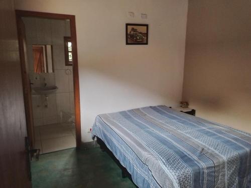 a bedroom with a bed and a bathroom with a sink at Chales rota da pedra in São Bento do Sapucaí