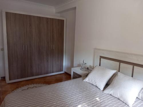 a bedroom with a bed and a wooden cabinet at A Redonda Vivienda Vacacional in Cangas de Morrazo