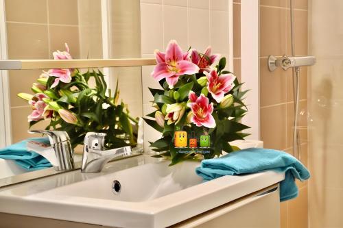 ein Waschbecken mit rosa Blumen im Spiegel in der Unterkunft Gite Caribou in Besse-et-Saint-Anastaise