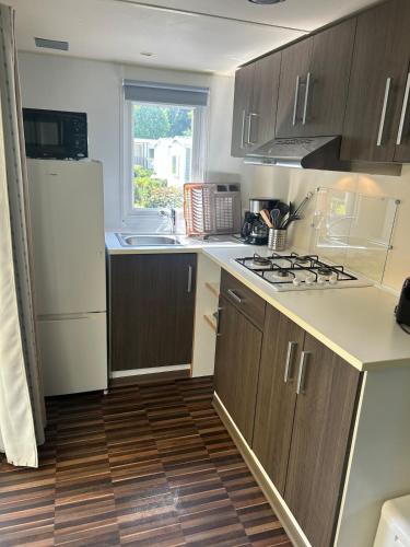 a kitchen with wooden cabinets and a white refrigerator at Cozy bungalow in Ivry-la-Bataille
