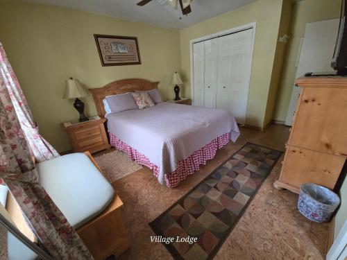 a bedroom with a bed and a chair at Village Lodge in Ruidoso