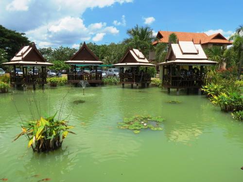 a pond in a garden with houses in it at Pongsin Resort in Khun Han