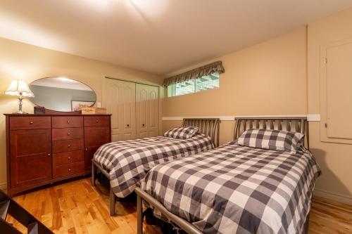 two beds in a room with a dresser and a mirror at Le Havre d'Émélie dogfriendly Lake access in Sainte-Émélie-de-lʼÉnergie