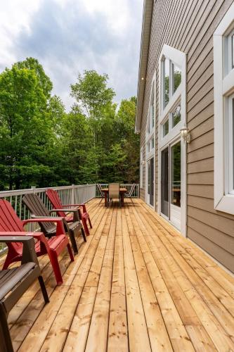 a wooden deck with benches and tables on a house at Le Havre d'Émélie dogfriendly Lake access in Sainte-Émélie-de-lʼÉnergie