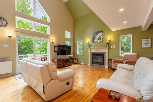 a living room with white furniture and a fireplace at Le Havre d'Émélie dogfriendly Lake access in Sainte-Émélie-de-lʼÉnergie