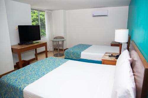 a hotel room with two beds and a television at Hotel Oceania Cartagena in Cartagena de Indias