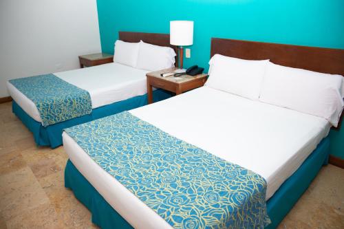 two beds in a hotel room with blue walls at Hotel Oceania Cartagena in Cartagena de Indias
