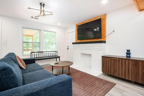 Una sala de estar con un sofá azul y un televisor en Chic 3BR Bungalow with Screened Porch & Patios, en Atlanta