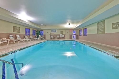 a large swimming pool with chairs and tables at Candlewood Suites Fort Wayne - NW by IHG in Fort Wayne